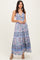 woman wearing a floral maxi dress with a knotted front and spaghetti straps, standing in a relaxed pose