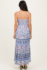 woman wearing a floral print maxi dress with smocked back and adjustable straps, standing with back to the camera