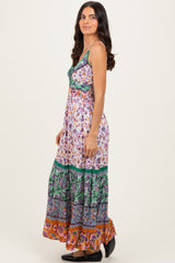 woman wearing a floral maxi dress with multiple colors and patterns, featuring a fitted bodice and flared skirt