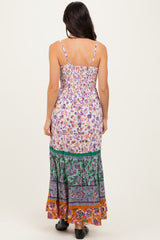 woman wearing a floral maxi dress with thin straps and a layered patterned skirt, view from the back