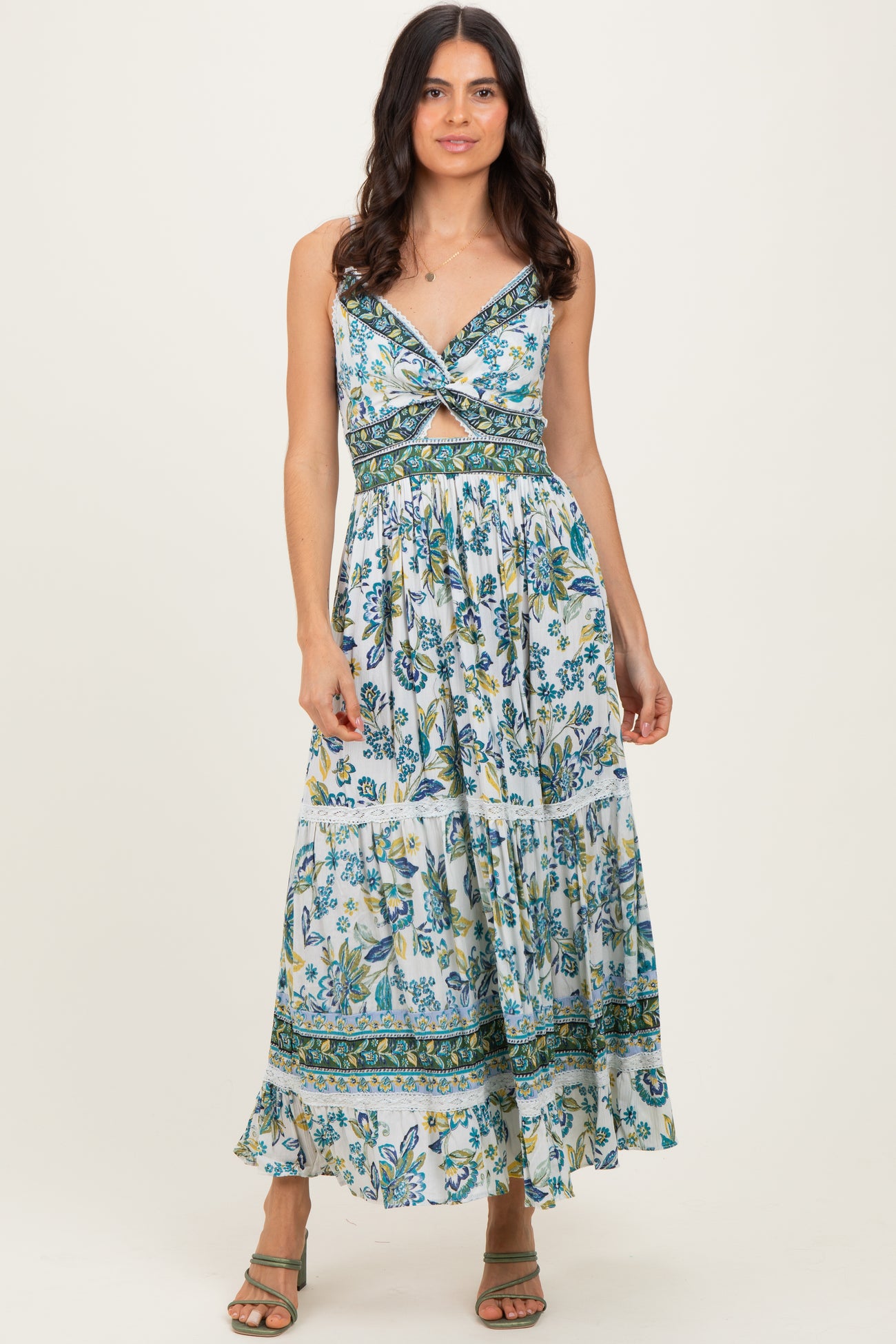 woman wearing a floral print maxi dress with a twist front and tiered skirt, styled with strappy sandals