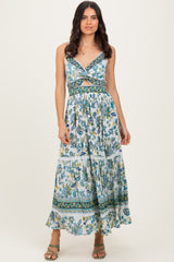 woman wearing a floral print maxi dress with a twist front and tiered skirt, styled with strappy sandals