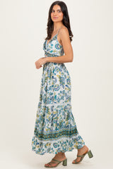 woman wearing a blue and green floral maxi dress with spaghetti straps and a tiered skirt