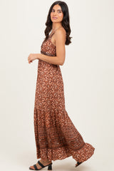 woman wearing a bohemian-style brown maxi dress with a patterned design and a tiered hem, posed sideways
