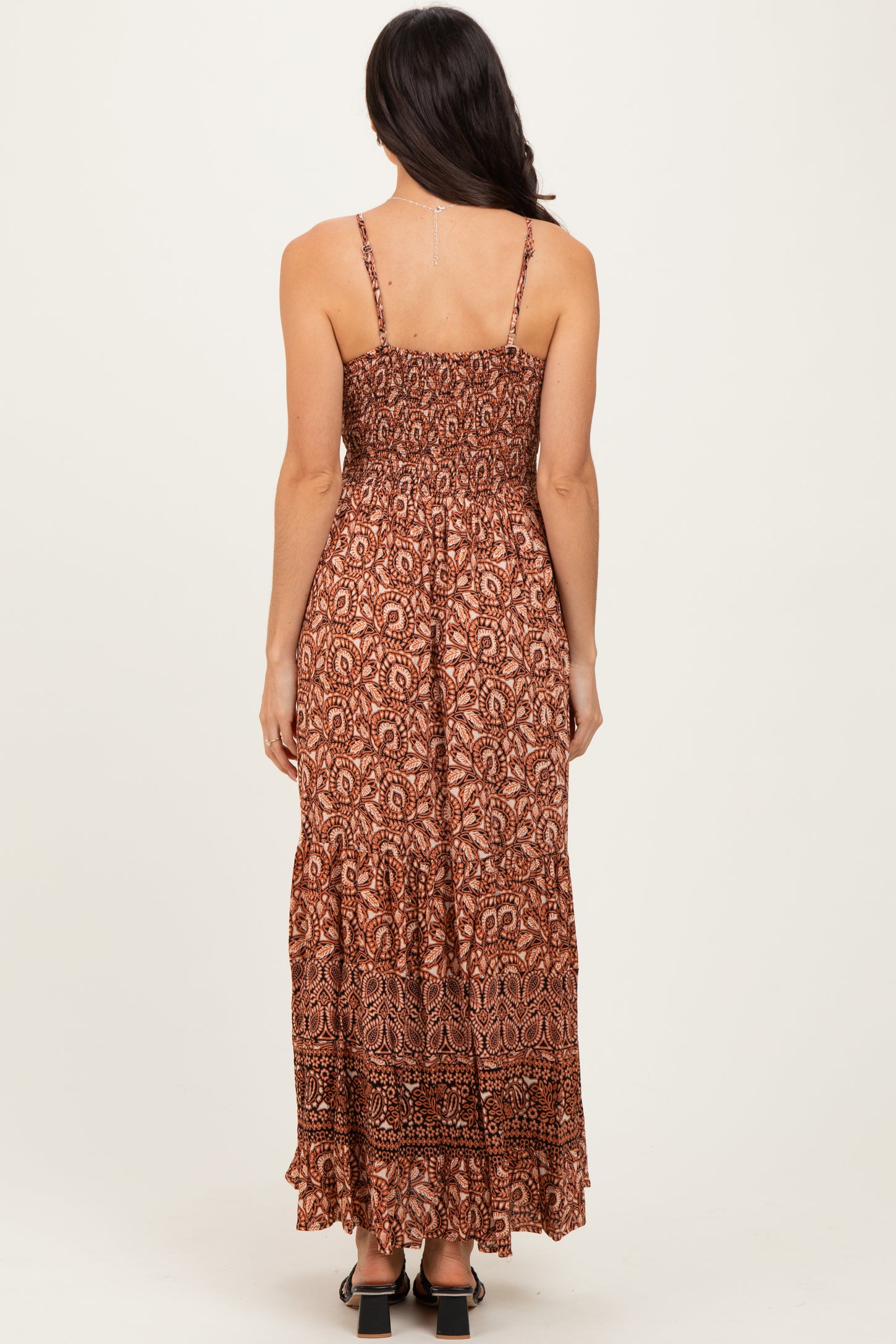 woman wearing a brown patterned maxi dress with spaghetti straps and a tiered skirt from the back