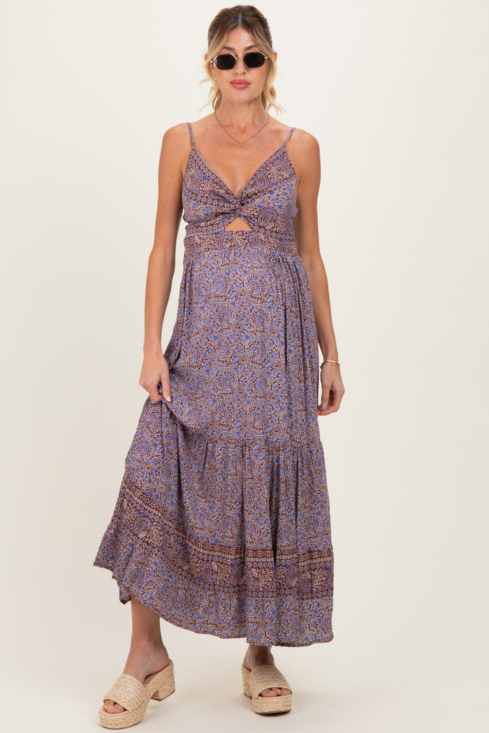 woman wearing a printed purple maternity maxi dress with a knot detail and a fitted bodice, displaying her baby bump