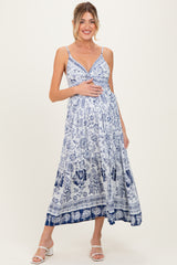 woman wearing a blue and white floral maternity maxi dress and holding her baby bump