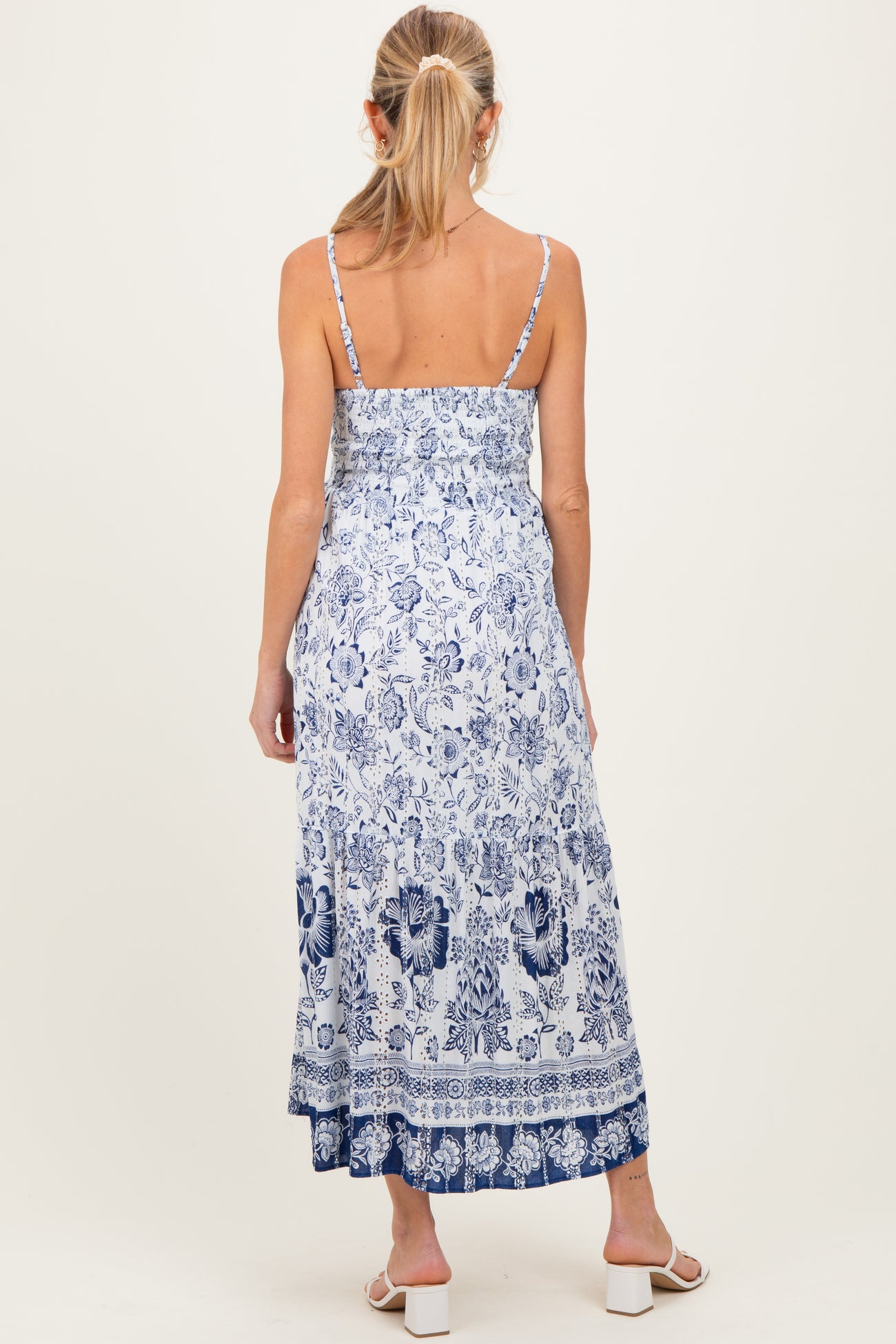 woman wearing a blue and white floral maternity maxi dress with spaghetti straps and a smocked back