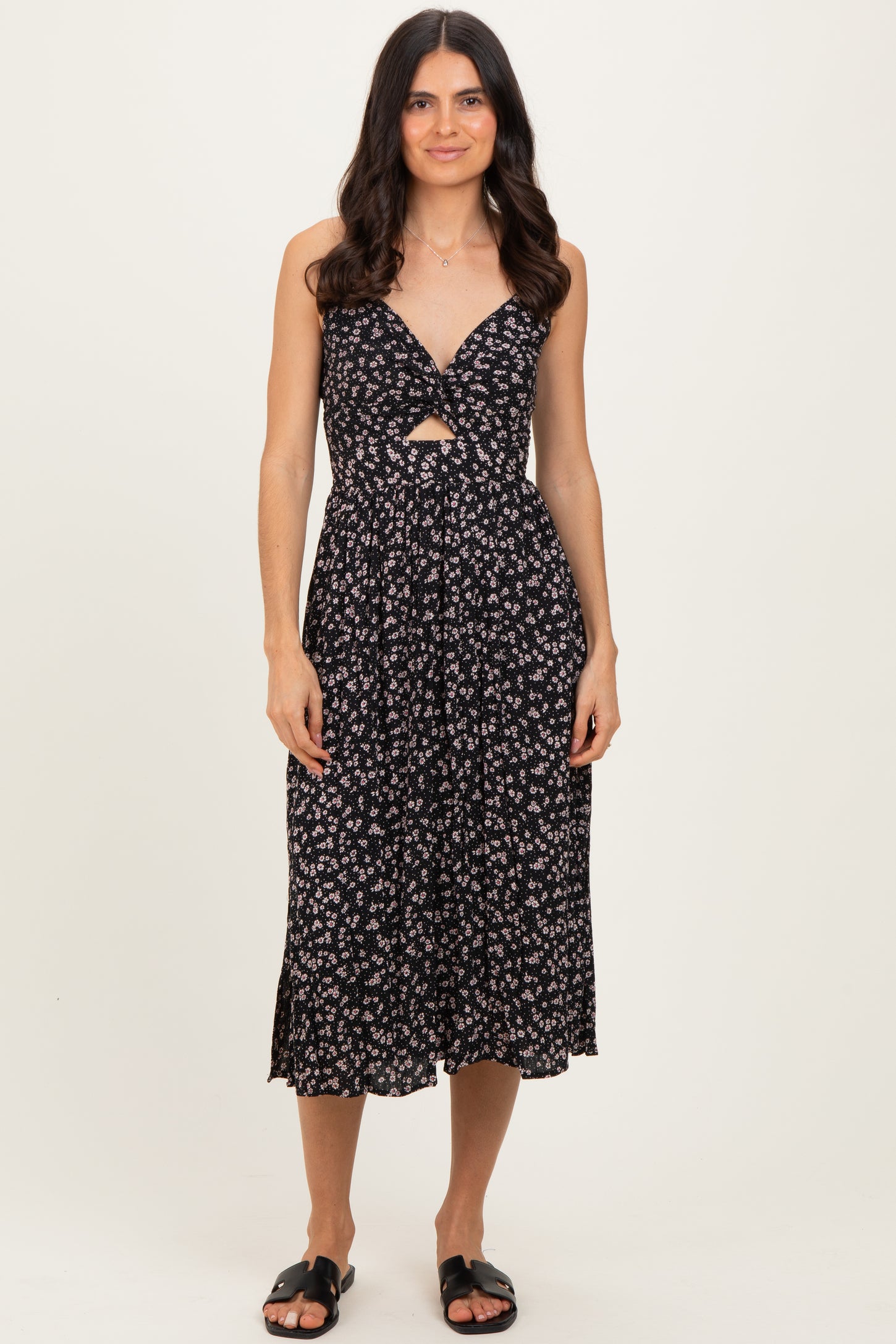 woman wearing a black floral print midi dress with a front cutout and spaghetti straps