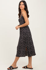woman wearing a black floral midi dress with spaghetti straps and a side slit, paired with black slide sandals