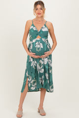 woman wearing a green floral maternity dress with a twist front and slit, showcasing her baby bump