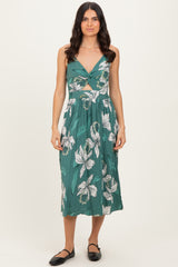 woman wearing a teal floral print midi dress with a knotted front detail and flared skirt