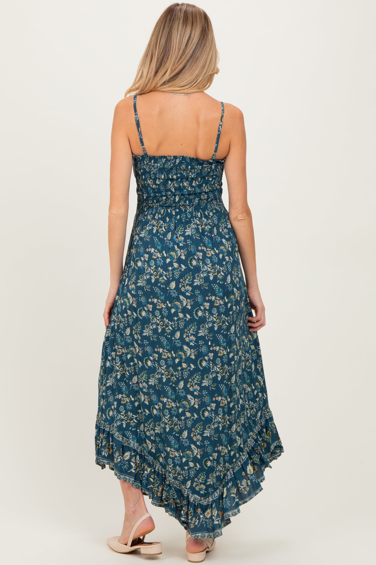 woman wearing a navy blue floral maternity maxi dress with adjustable straps and a tiered hemline, showing her baby bump
