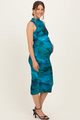 woman wearing a teal floral print maternity dress with ruched details and a visible baby bump