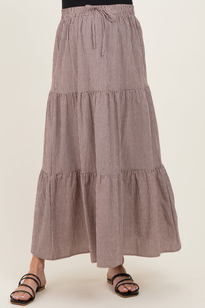 maternity wear in a brown and white checked maxi skirt with tiers and an adjustable tie waist, model wearing it