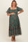 woman wearing a green floral maternity maxi dress with puff sleeves and holding her baby bump