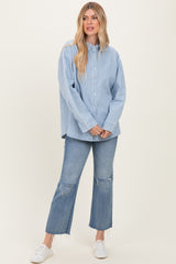 woman wearing a light blue striped button-up shirt and distressed flare jeans with white sneakers