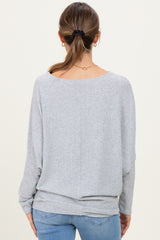 woman wearing a light gray maternity sweater with a loose fit and drop sleeves, viewed from the back