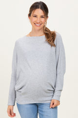 woman wearing a light gray long sleeve maternity top with a relaxed fit and gathered detail, smiling at the camera
