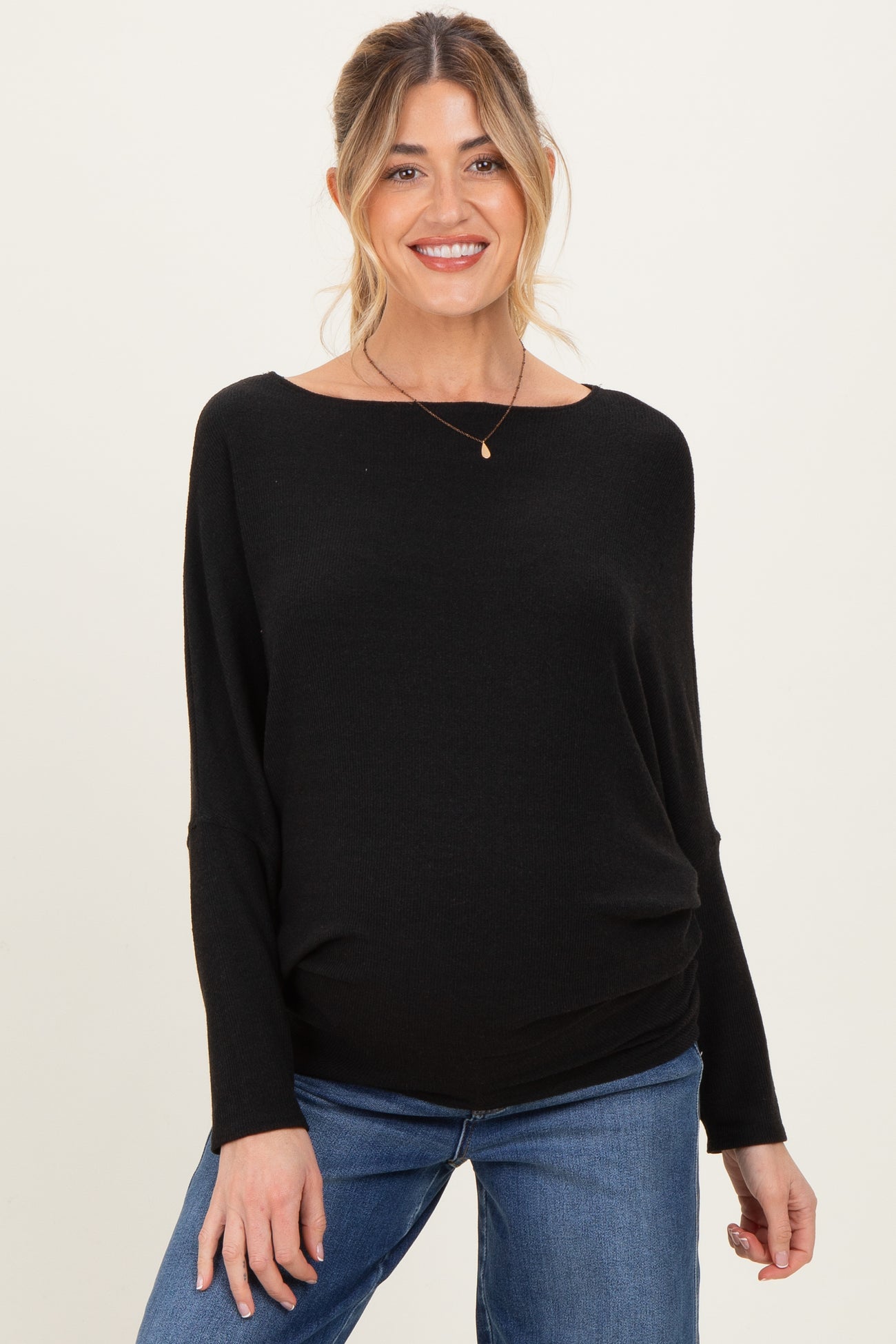 woman wearing a black maternity top with a relaxed fit and gathered detail at the waist, paired with jeans