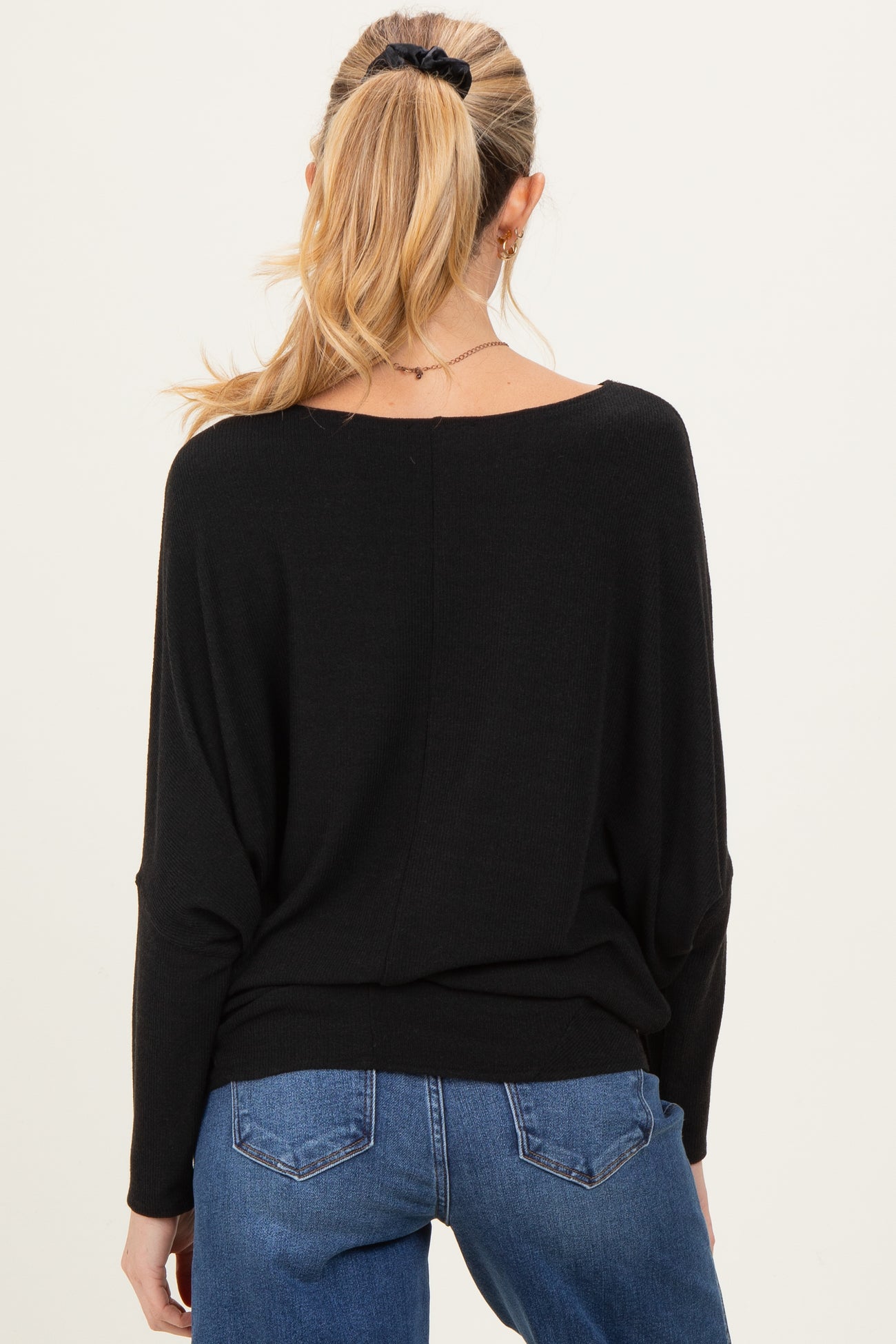 woman wearing a black maternity sweater, styled with a relaxed fit, showing the back view