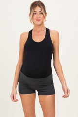 woman wearing a black maternity tank top and gray maternity shorts, showing her baby bump