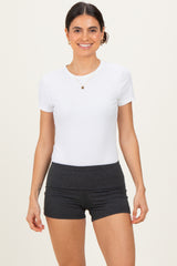 woman wearing a white short sleeve fitted t-shirt and dark gray high-waisted shorts