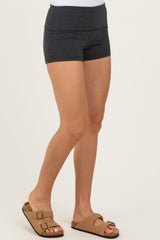 woman wearing dark gray high-waisted athletic shorts with a fitted style and tan sandals
