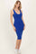 woman wearing a bright blue ribbed midi dress with a deep v-neck and styled with white sneakers