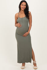 woman wearing an olive green maternity maxi dress with adjustable straps and a side slit, holding her baby bump
