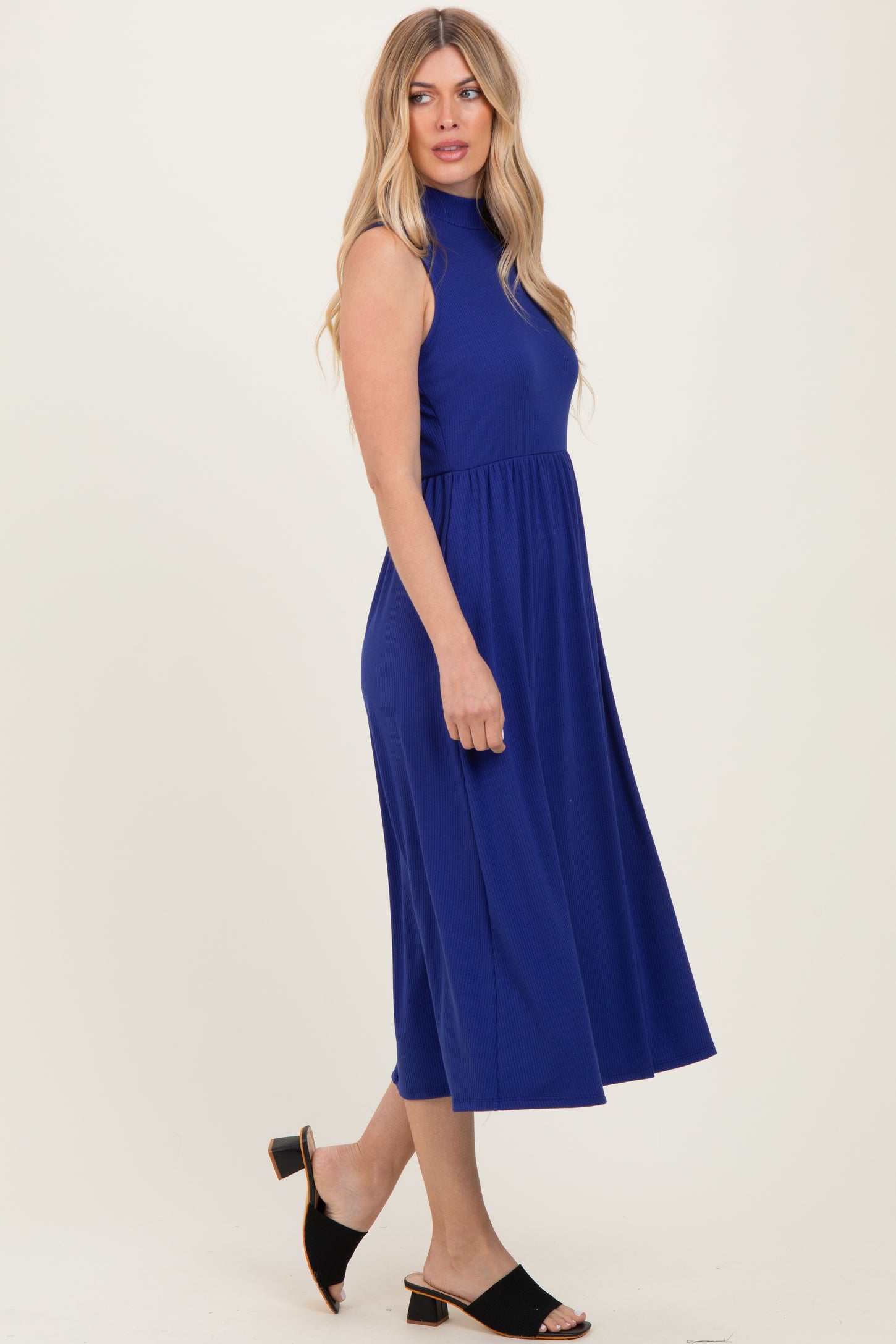 woman wearing a sleeveless royal blue midi dress with a high neck and flared skirt