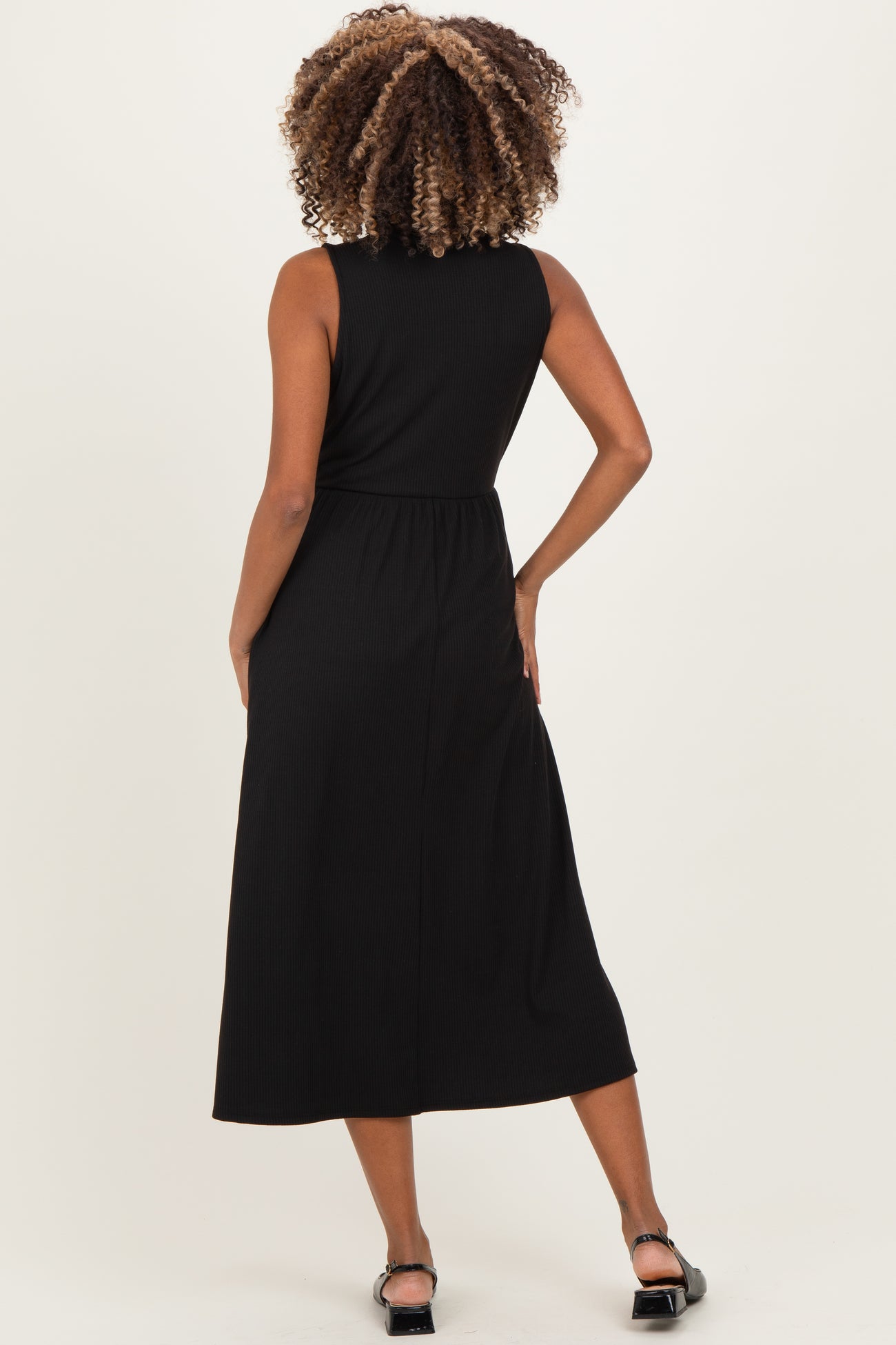 woman wearing a black sleeveless midi maternity dress, showing the back view