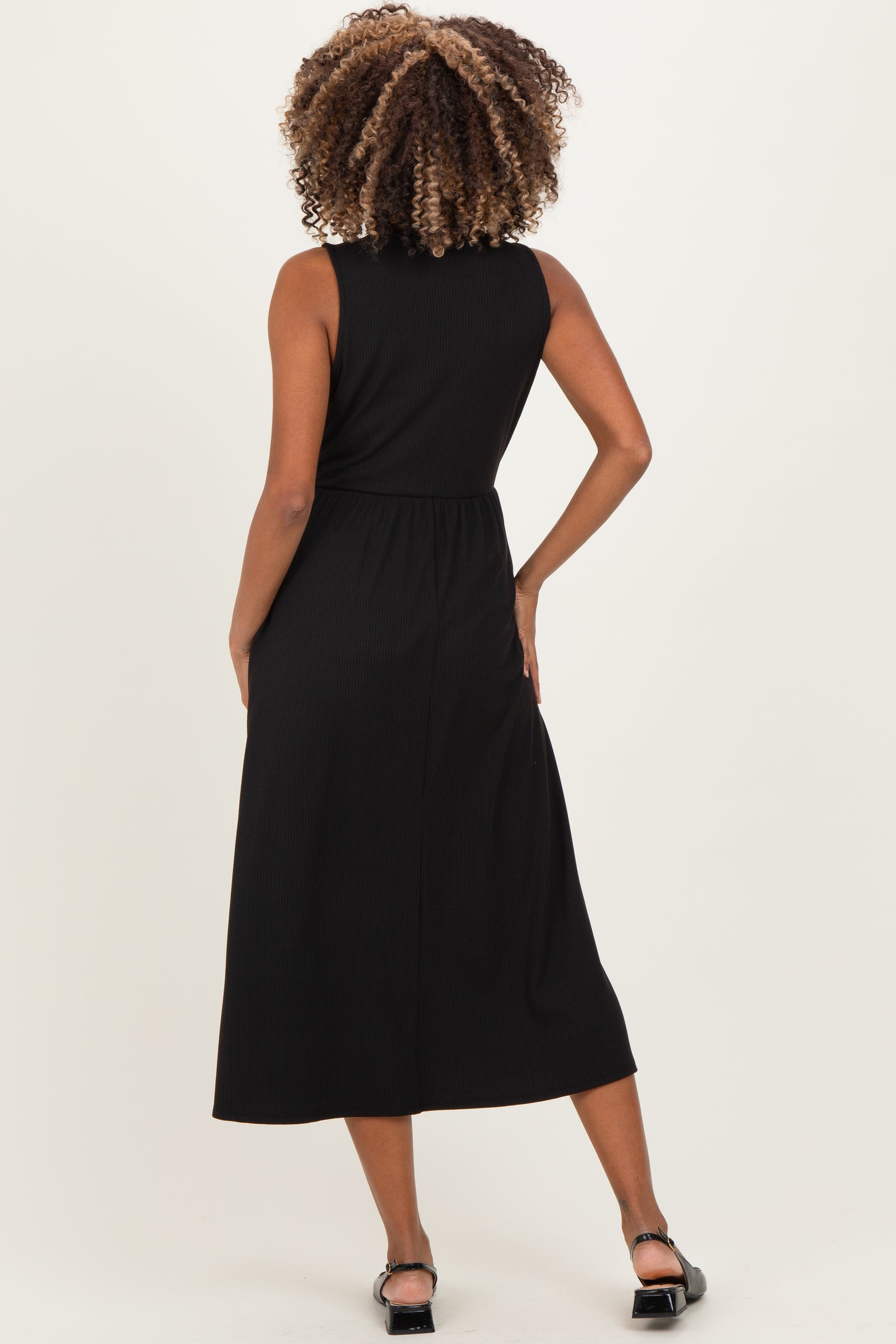 woman wearing a black sleeveless midi maternity dress, showing the back view