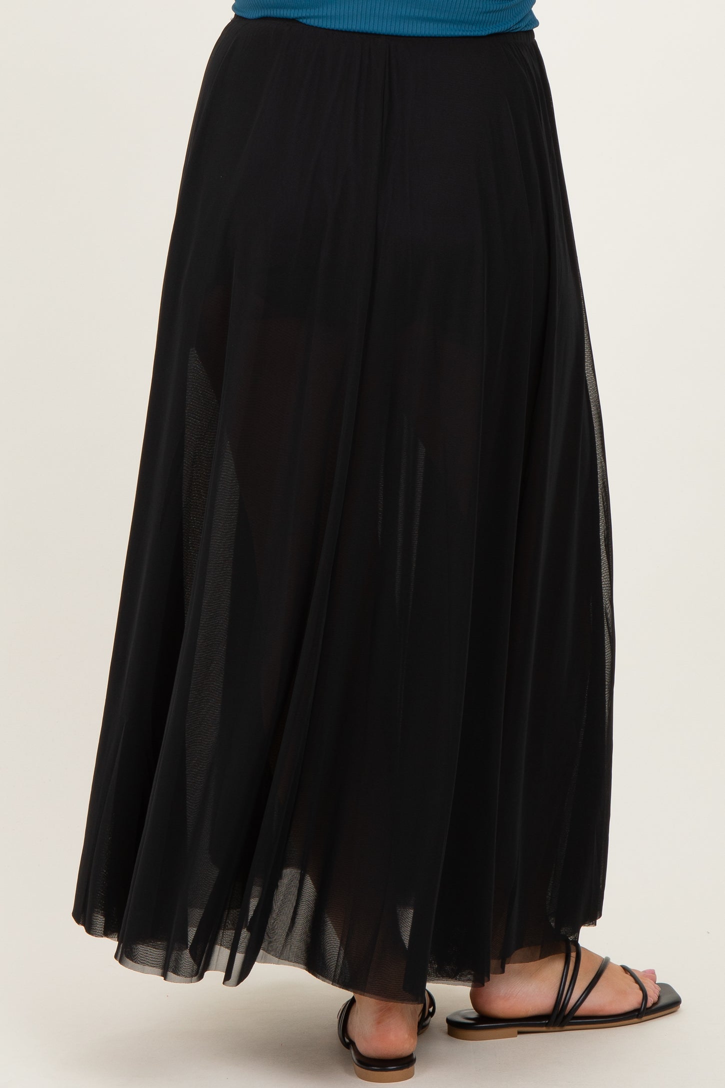 maternity wear black flowy maxi skirt with sheer overlay, model shown from the back wearing flat sandals
