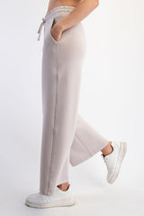 woman wearing light gray wide-leg sweatpants with pockets and drawstring, styled with white sneakers