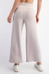 woman wearing light beige wide-leg sweatpants, showing the back view with an elastic waistband and casual style
