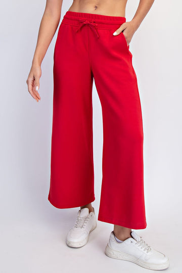 woman wearing red wide-leg jogger pants with an elastic waistband and drawstring, paired with white sneakers