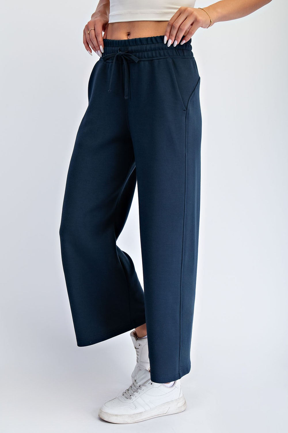 woman wearing navy blue wide-leg sweatpants with an elastic waistband and drawstring, paired with white sneakers