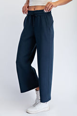 woman wearing navy blue wide-leg sweatpants with an elastic waistband and drawstring, paired with white sneakers