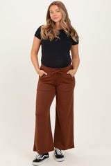 woman wearing a black maternity t-shirt and brown wide-leg maternity pants with pockets and drawstring, smiling