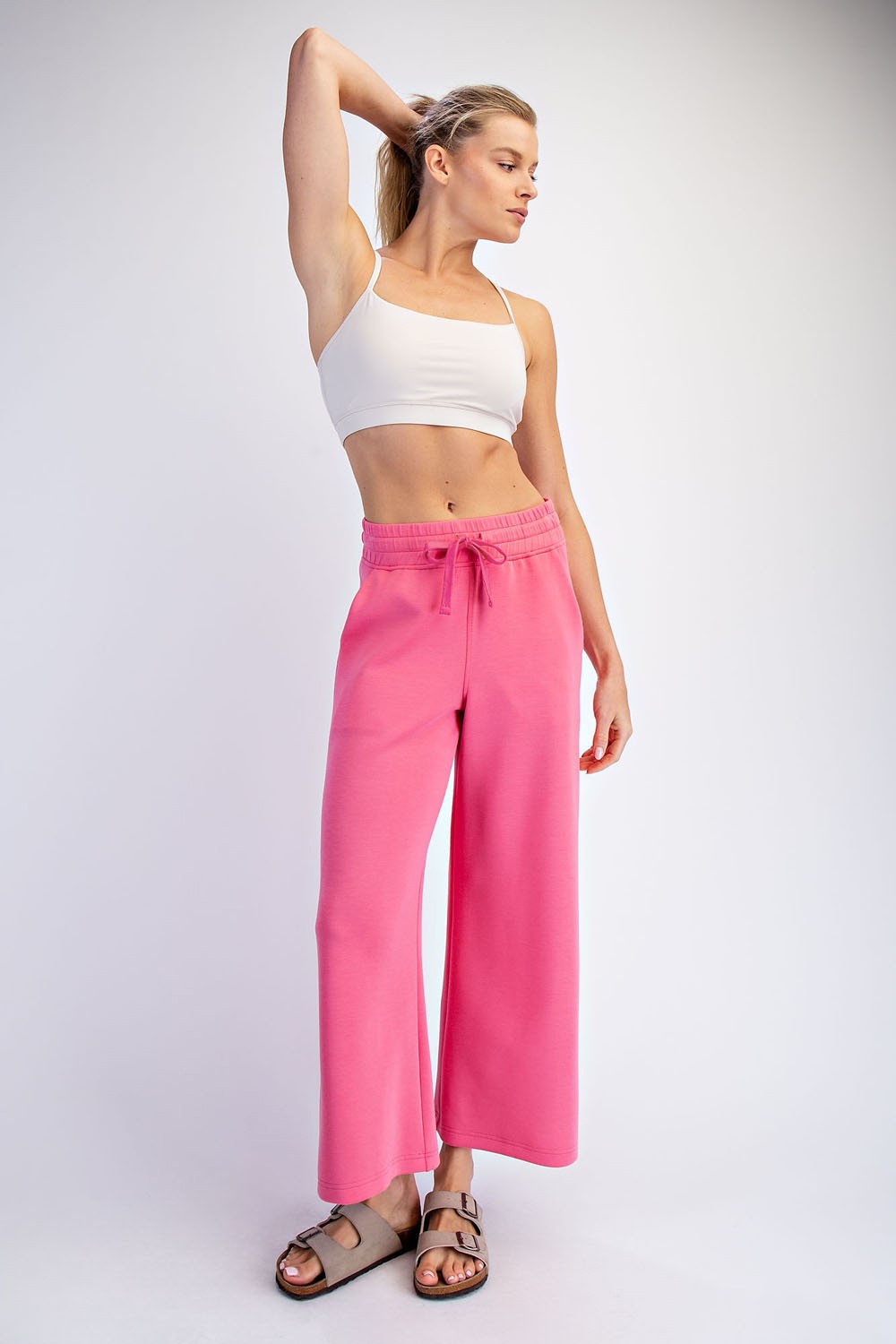 woman wearing a white crop top and pink wide-leg pants with a drawstring waist
