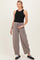 woman wearing a black ribbed maternity tank top and light gray wide-leg maternity pants, holding her baby bump
