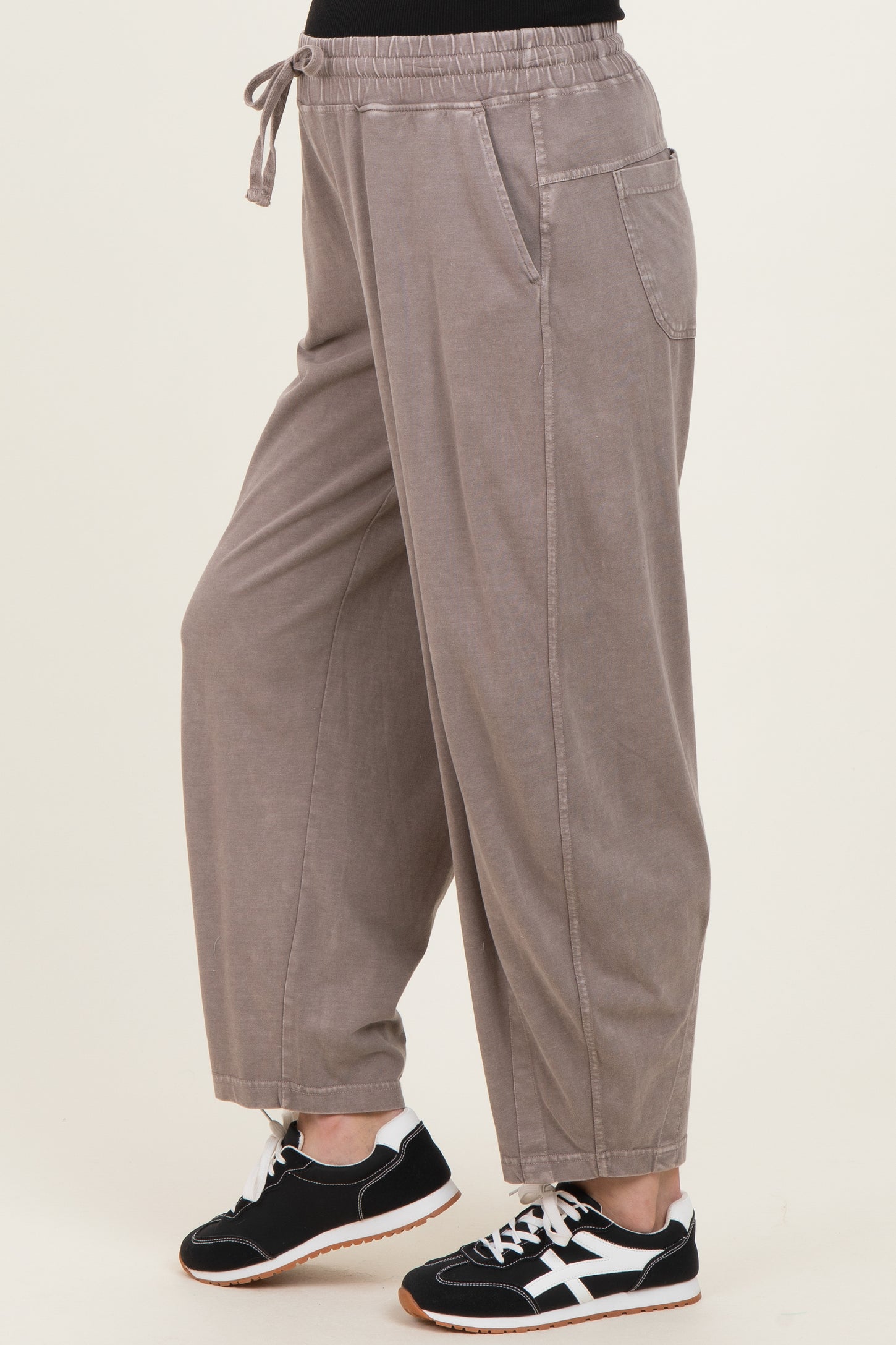 woman wearing taupe maternity jogger pants with an elastic waistband and side pockets, styled with black sneakers