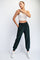 woman wearing a cream cropped tank top and dark green jogger pants with elastic waistband and cuffs