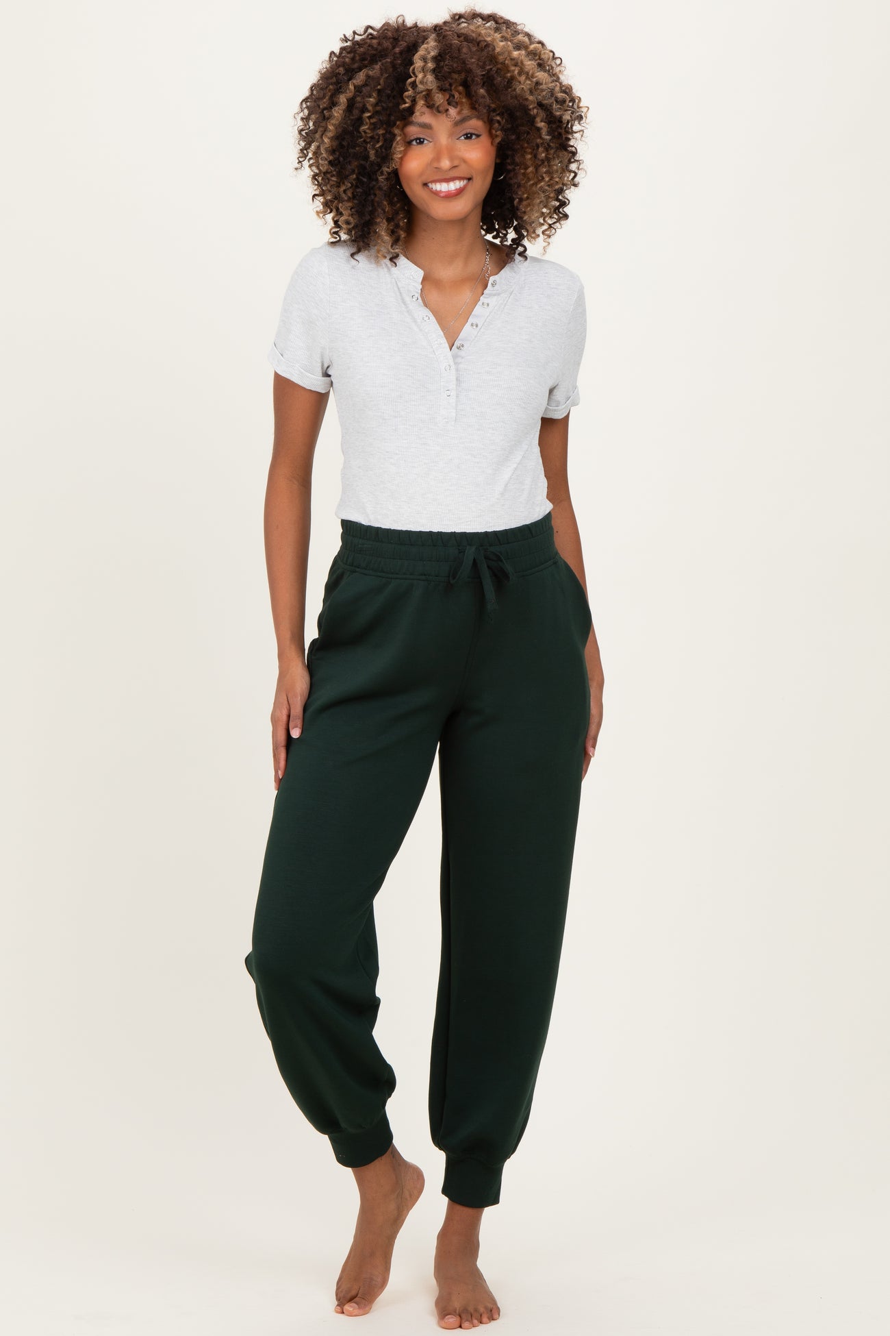 woman wearing a gray short sleeve maternity top and green jogger pants with a relaxed fit and elastic waistband, no baby bump visible