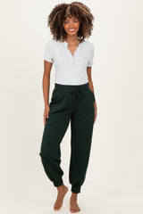 woman wearing a gray short sleeve maternity top and green jogger pants with a relaxed fit and elastic waistband, no baby bump visible