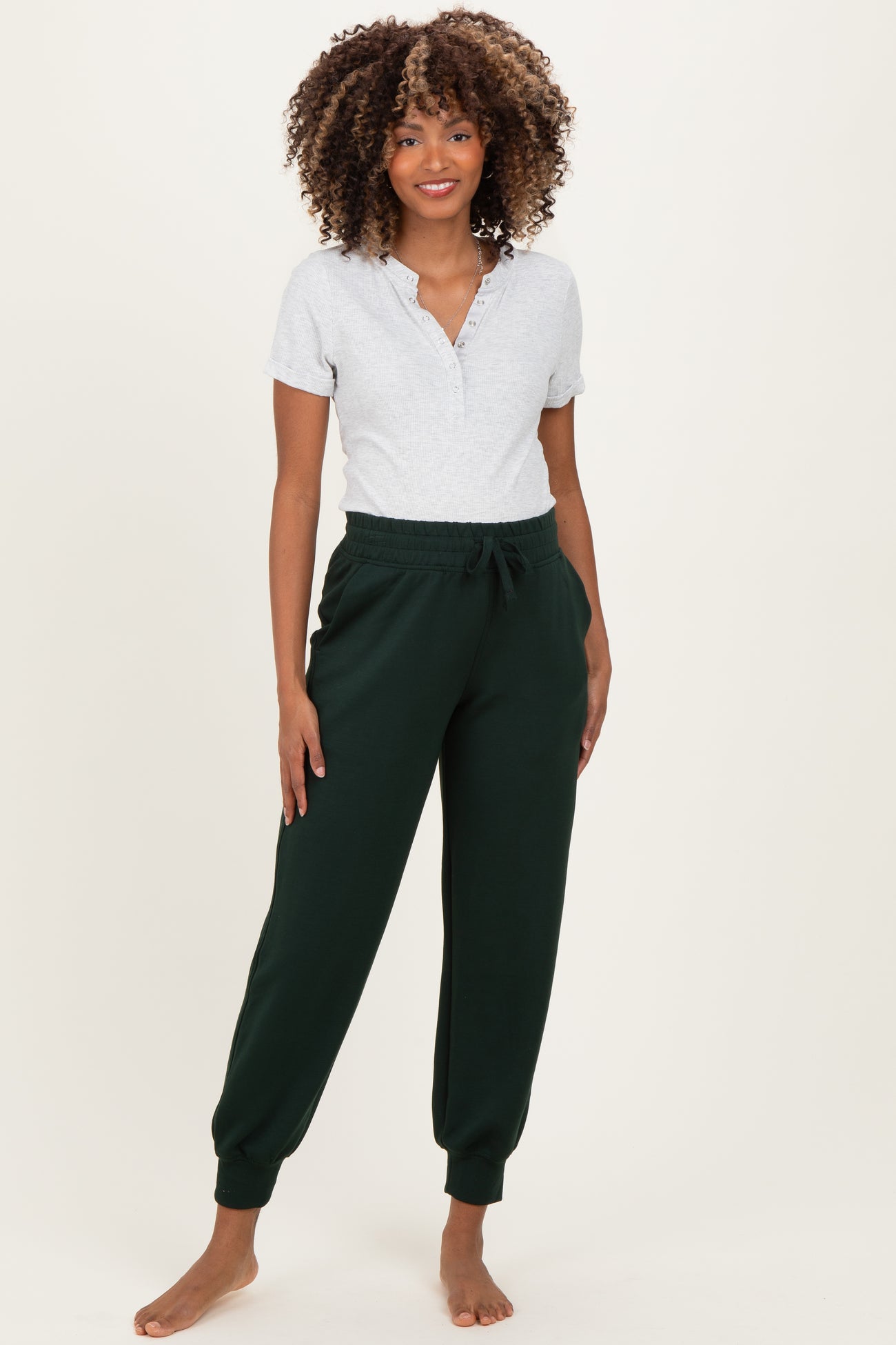 woman wearing a gray short sleeve henley top and green maternity jogger pants