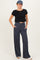 woman wearing a black cropped t-shirt and navy wide-leg pants with pockets, styled casually with a cap