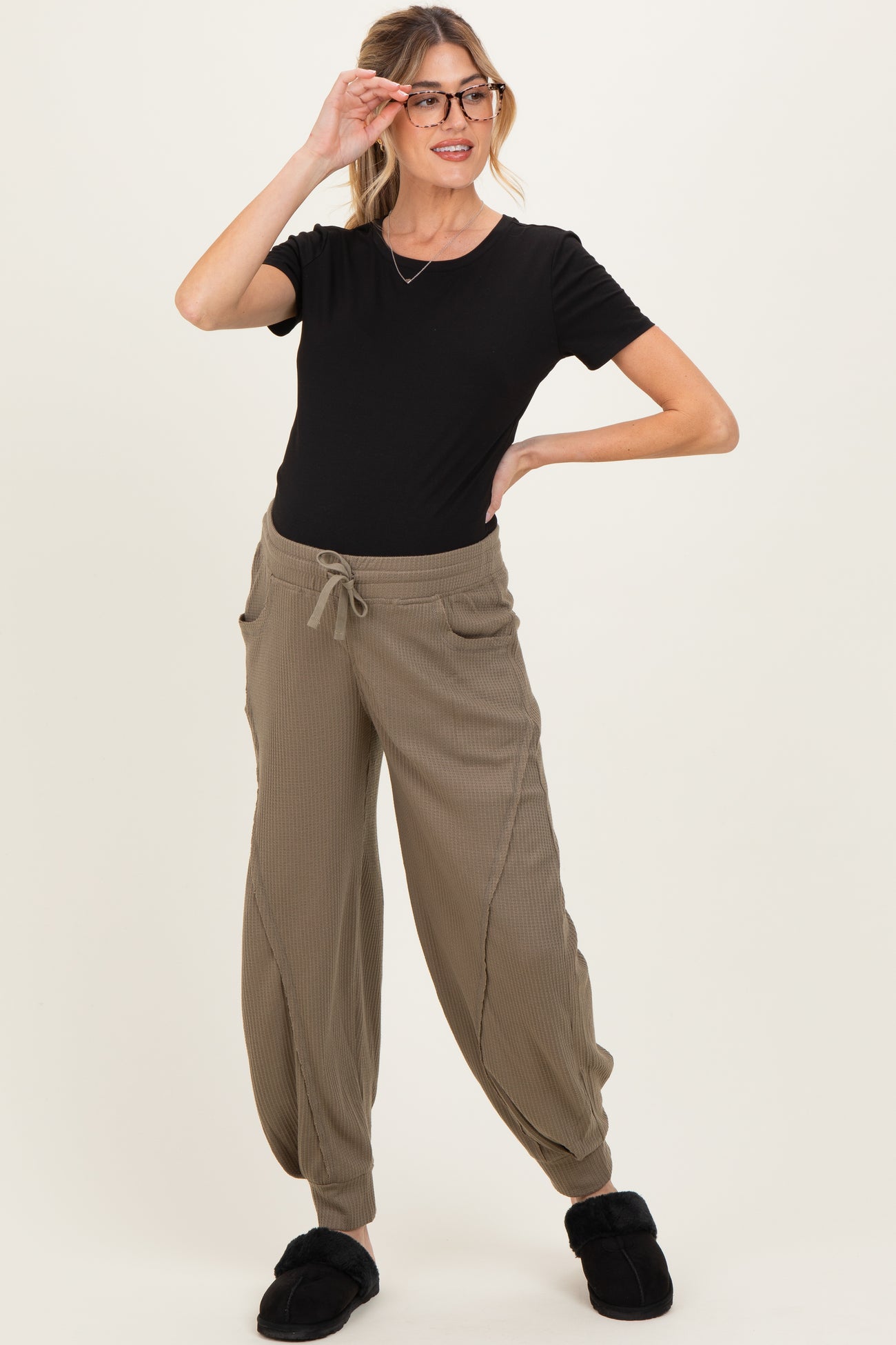 woman wearing a black short sleeve maternity top and khaki ribbed maternity joggers with pockets and drawstring