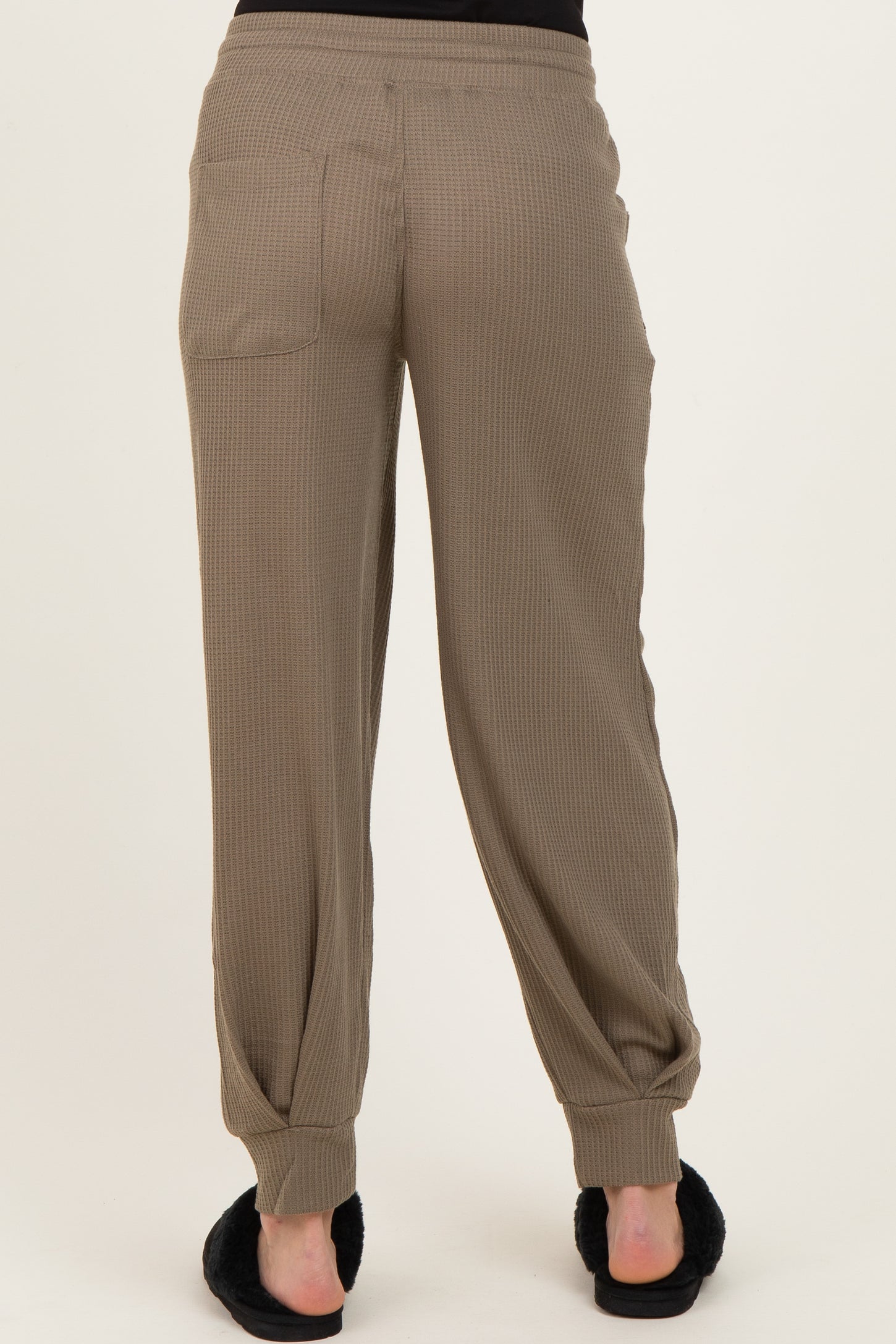 woman wearing khaki ribbed maternity jogger pants, showing the back view with side pockets and elastic cuffs